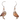 A pair of dangle earrings featuring two burrowing owls made from recycled paperboard. The earrings have a silver-toned hook and bead. The background of the packaging shows a prairie landscape. The packaging also includes the text "Jabebo Studio Inspire Curiosity" and "Burrowing Owl Made with cereal box paperboard."