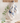 A tea towel hanging on a wooden rack in a kitchen setting. The tea towel features an "Ocean" design with various puffins, whales, and other sea creatures. A small plant, a glass vase, a gold spoon, a white bowl, and a cutting board are also visible on the kitchen counter.